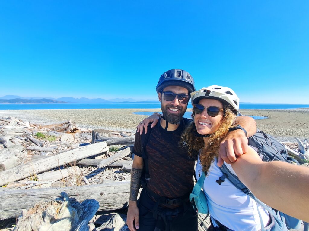 A couple of cyclists posing on a beach in Canada